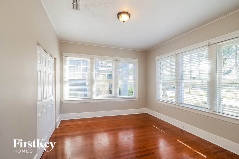 an empty room with wooden floors and three windows