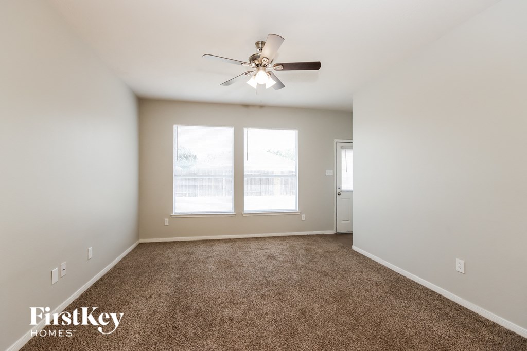 A room with a carpeted floor and a ceiling fan.