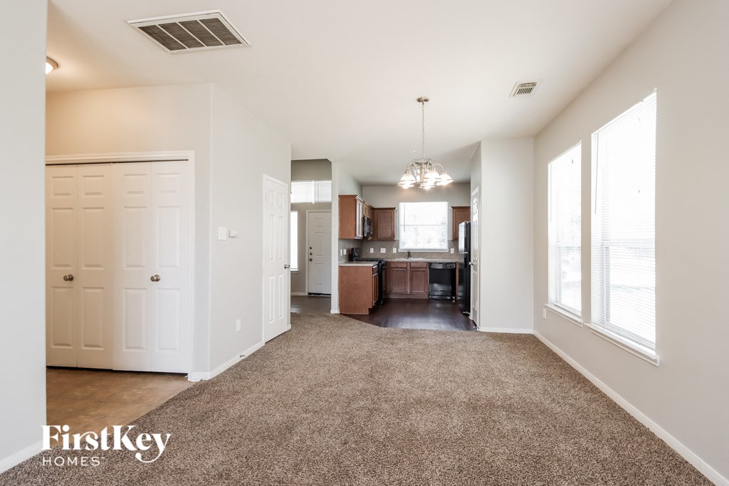 A spacious living room with a kitchen in the background.