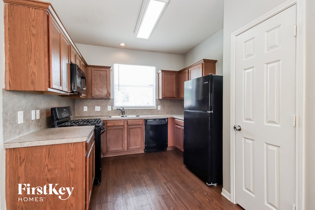 A kitchen with wooden cabinets and a black refrigerator.