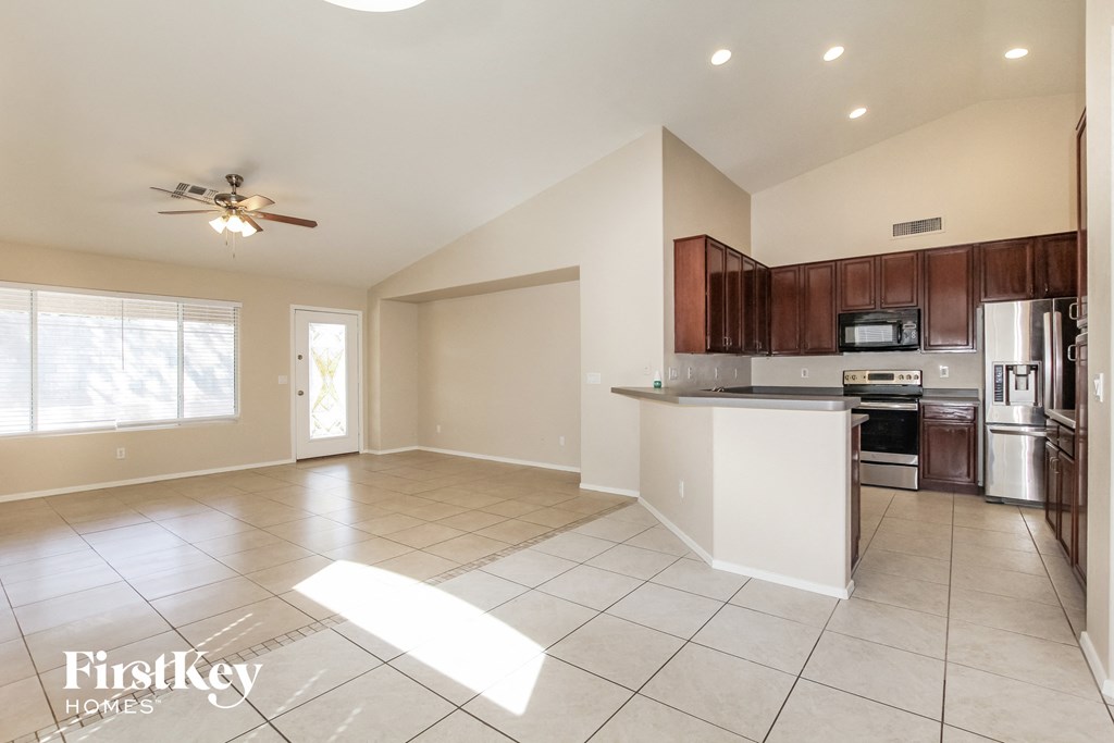 an open kitchen and living room with tile flooring and a ceiling fan