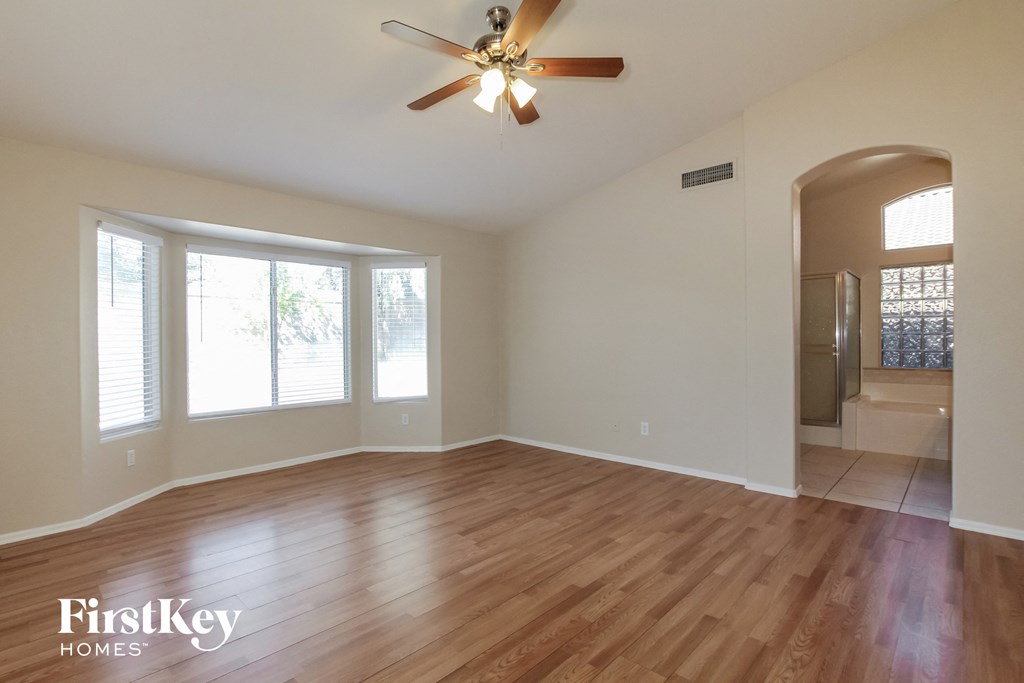 an empty living room with wood floors and a ceiling fan