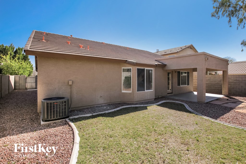 a beige house with a yard and a trash can
