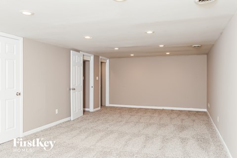 A spacious room with carpeted floor and white walls.