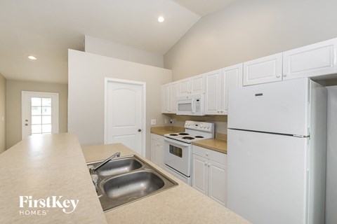 a kitchen with white cabinets and white appliances and a white refrigerator