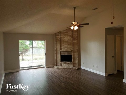 an empty living room with a fireplace and a ceiling fan