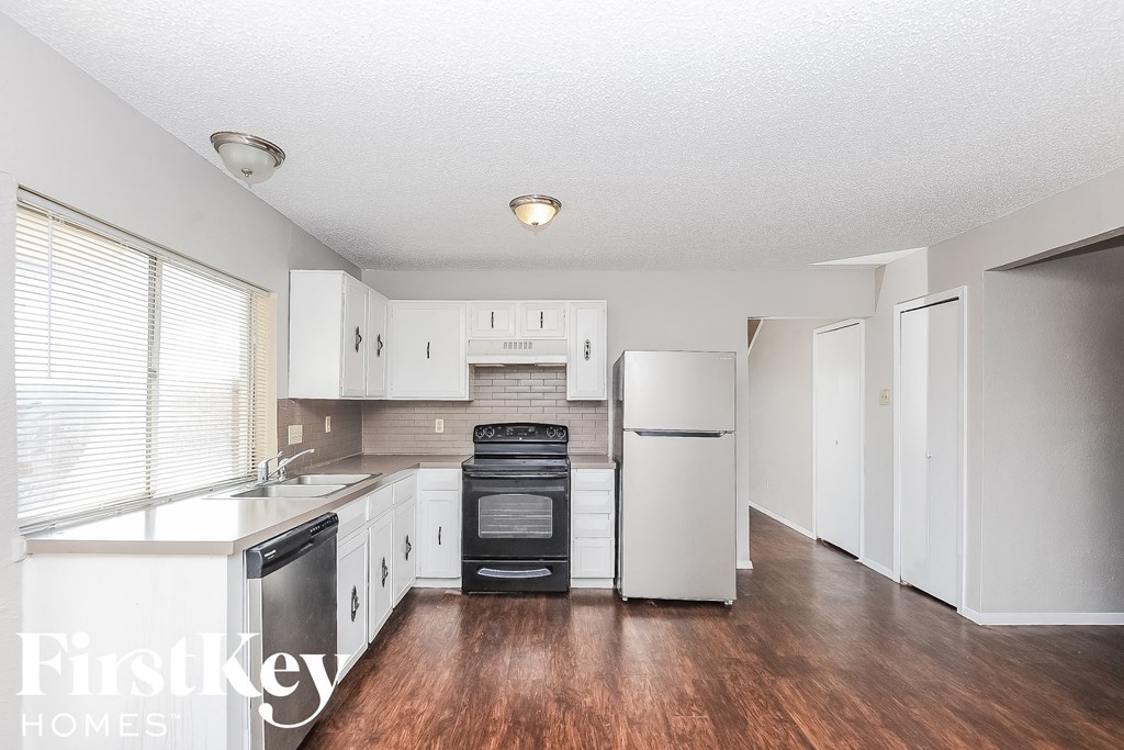 a kitchen with white cabinets and a refrigerator and a sink