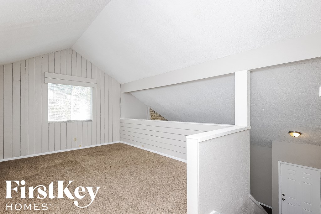 a small attic bedroom with white walls and a window