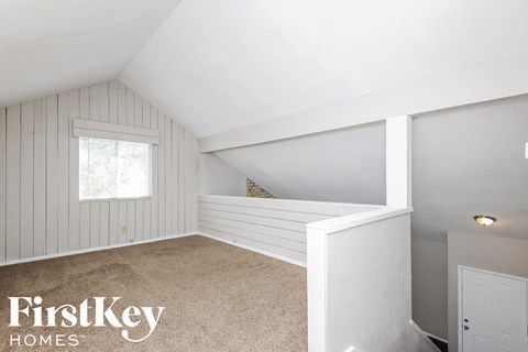 a small attic bedroom with white walls and a window