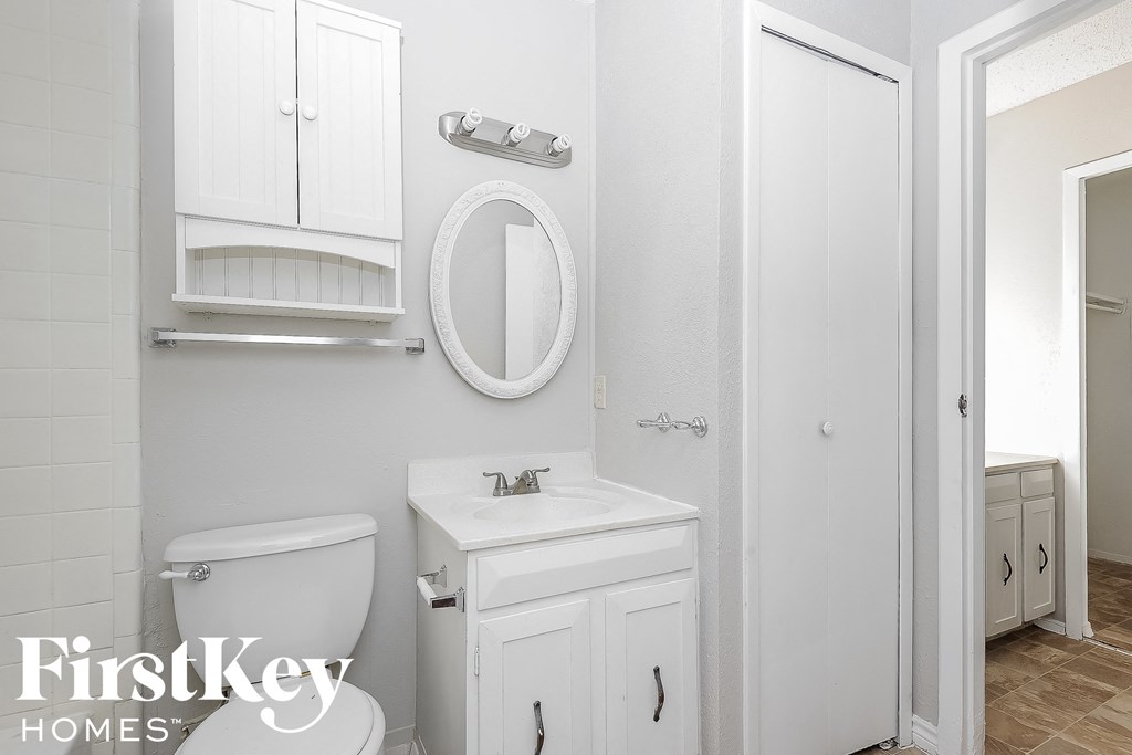 a white bathroom with a toilet and a sink and a mirror