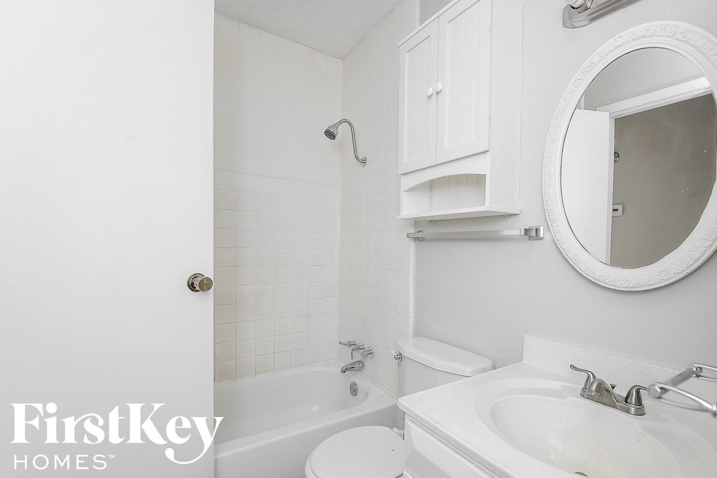 a white bathroom with a white sink and toilet and a bath tub