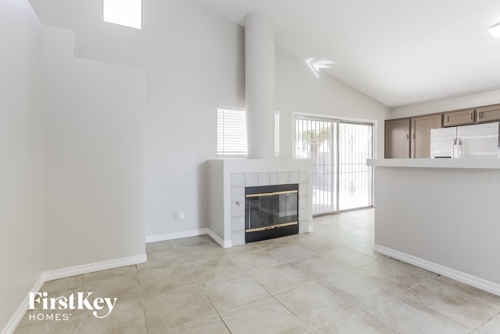 A spacious living room with a fireplace and a kitchen area in the background.