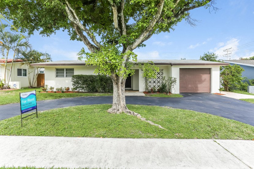 a house with a driveway and a tree in front of it