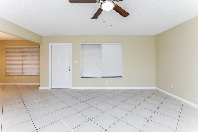 an empty living room with a ceiling fan