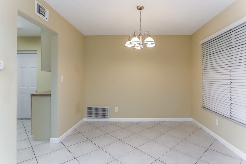 an empty living room with a white tile floor and a chandelier