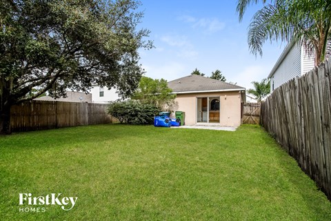 a backyard with a house and a yard with grass and a fence