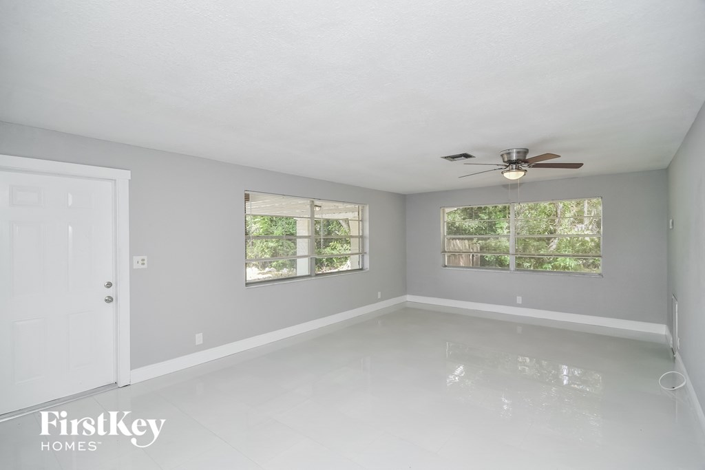 a empty room with a ceiling fan and two windows