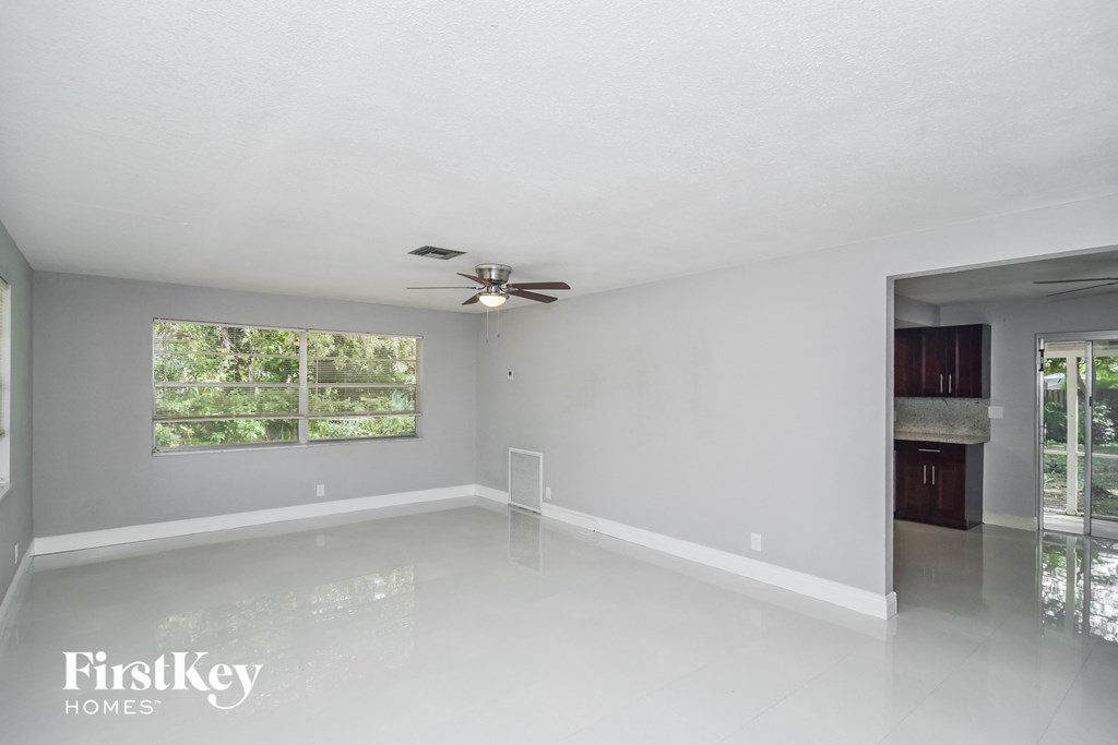an empty living room with a ceiling fan and a window