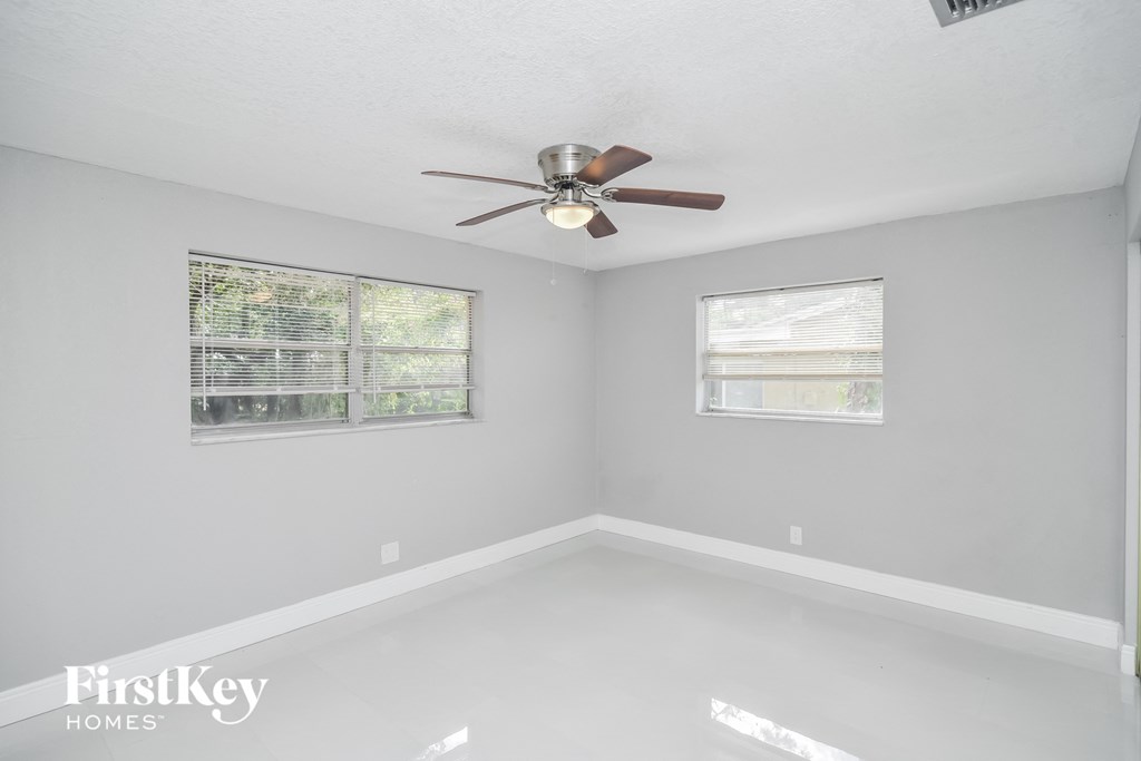 a bedroom with a ceiling fan and two windows