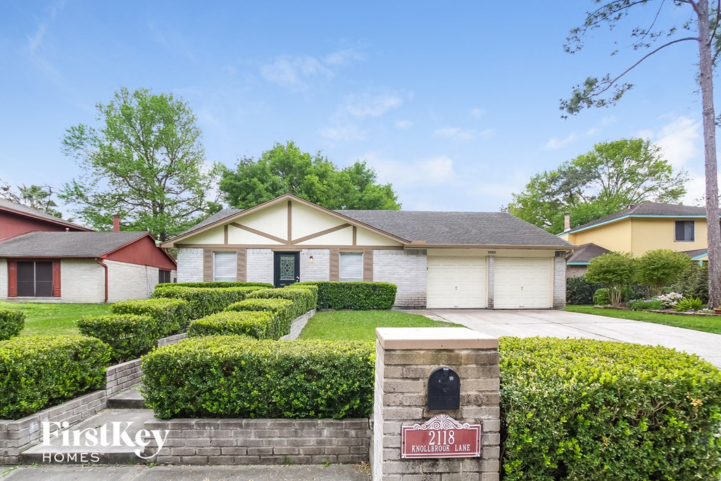 a home with manicured hedges in front of a driveway