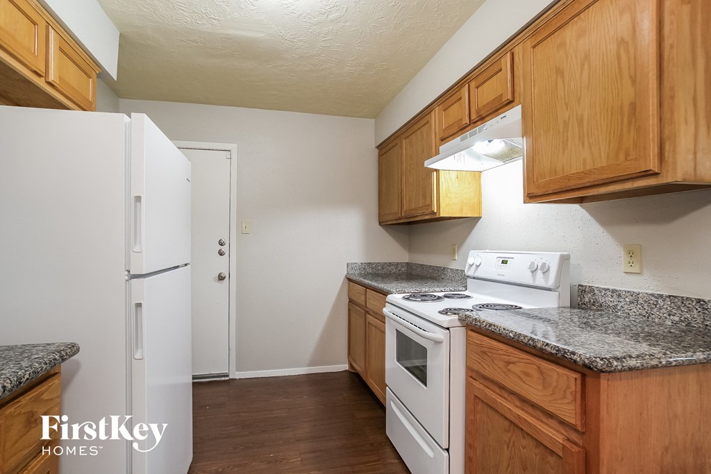 a kitchen with wood cabinets and white appliances and a refrigerator