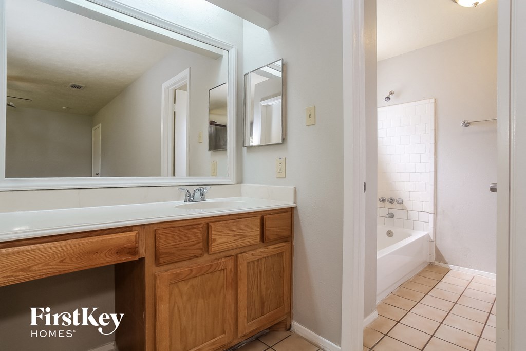 the master bathroom has a large vanity and a large mirror