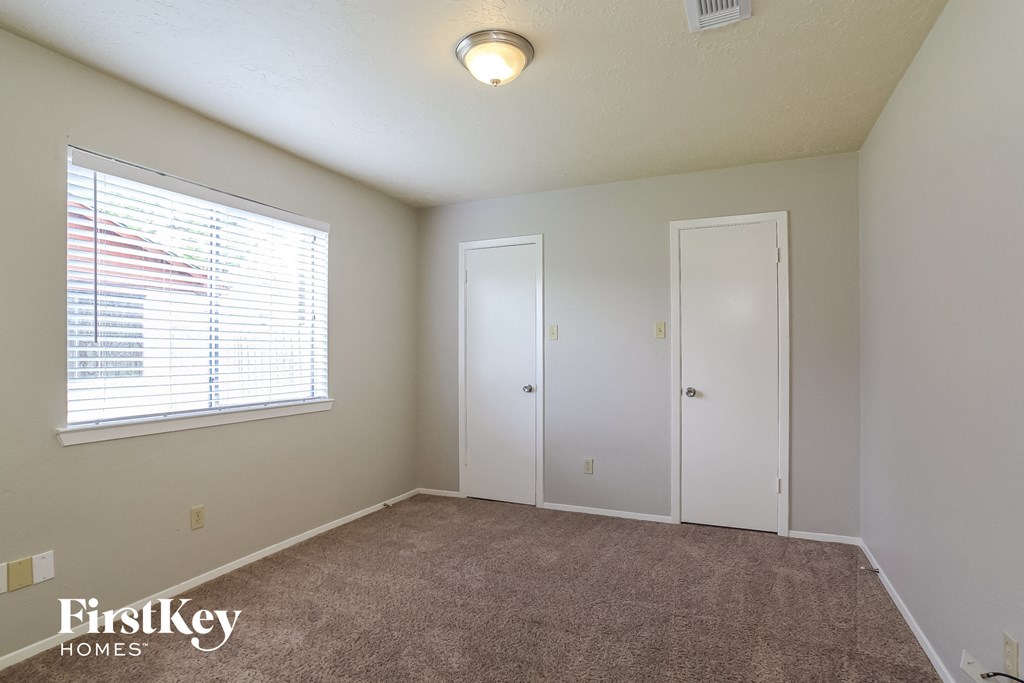 the living room of an apartment with a large window and carpeting