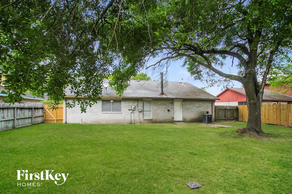 a backyard with a white house and a tree