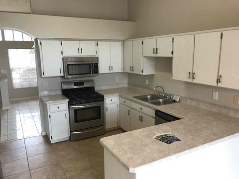 A kitchen with white cabinets and a beige countertop.