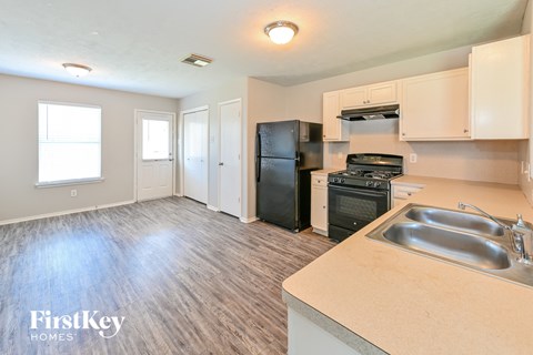 A kitchen with a black refrigerator and stove, and a sink with a wooden counter.