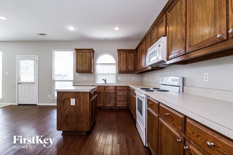 A kitchen with wooden cabinets and a white stove top oven.