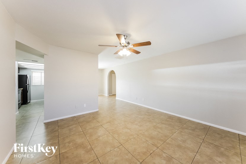 a spacious living room with tile flooring and a ceiling fan