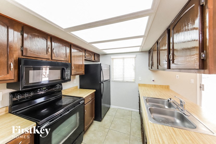a kitchen with black appliances and wooden cabinets and a window