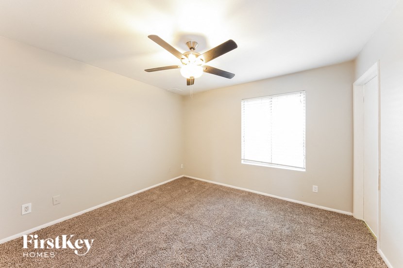 the spacious living room with ceiling fan and carpet