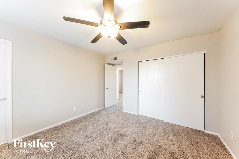 a spacious living room with a ceiling fan and a closet