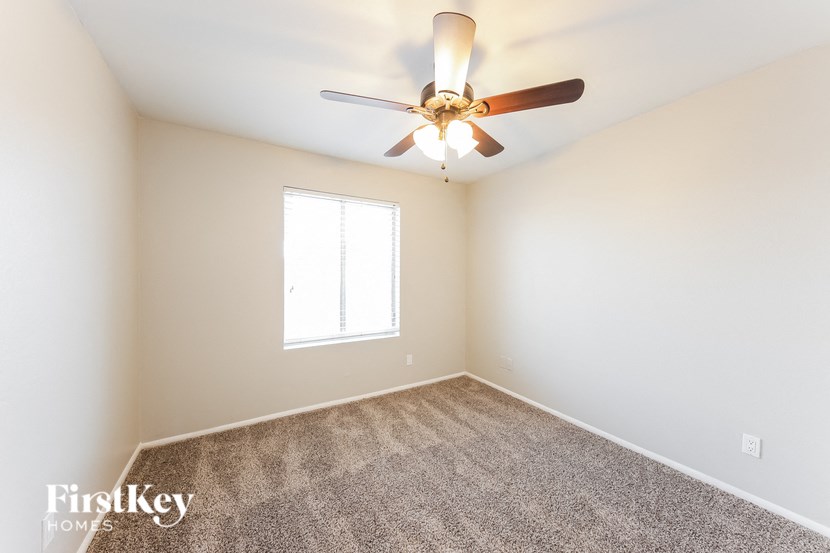 a bedroom with a ceiling fan and a carpet