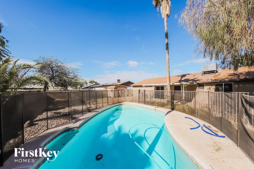 a pool with a fence around it and a house in the background
