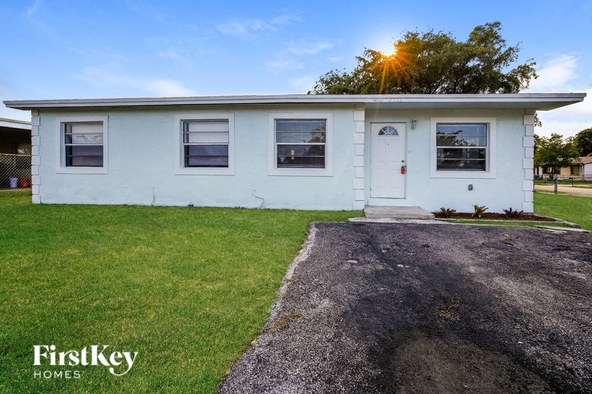 A white house with a gravel driveway in front.