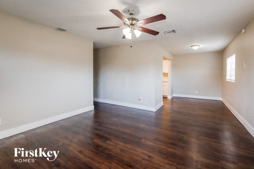 A spacious room with a ceiling fan and wooden flooring.