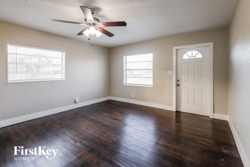 A room with a ceiling fan and wooden floors.