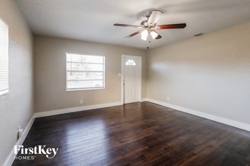 A room with a ceiling fan and wooden flooring.