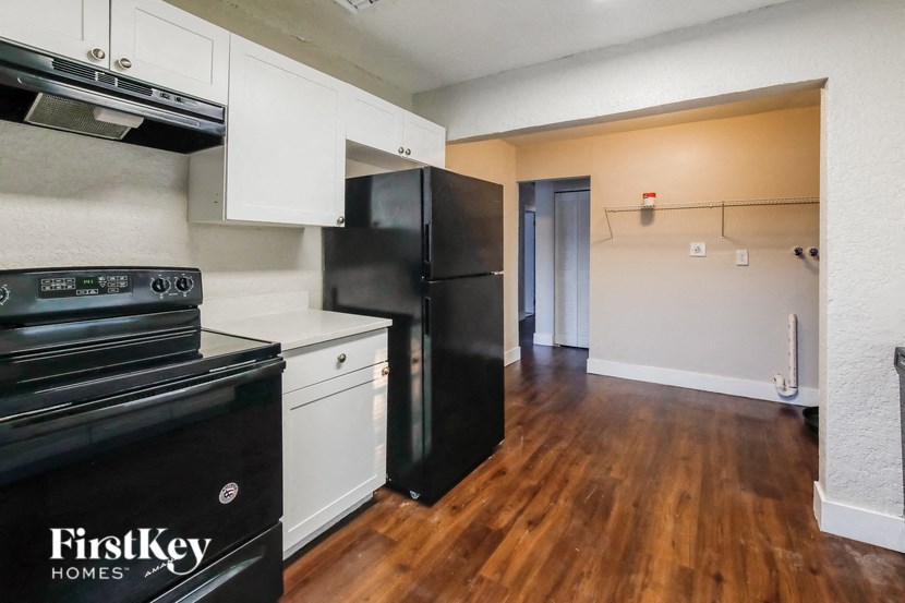 A kitchen with black appliances and wooden floors.