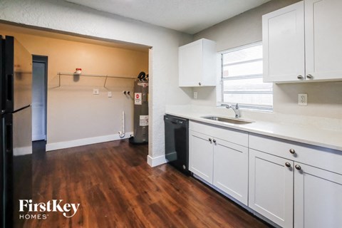 A kitchen with white cabinets and a wooden floor.