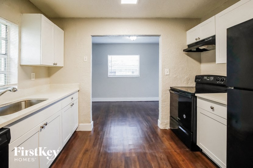 A kitchen with black appliances and white cabinets.