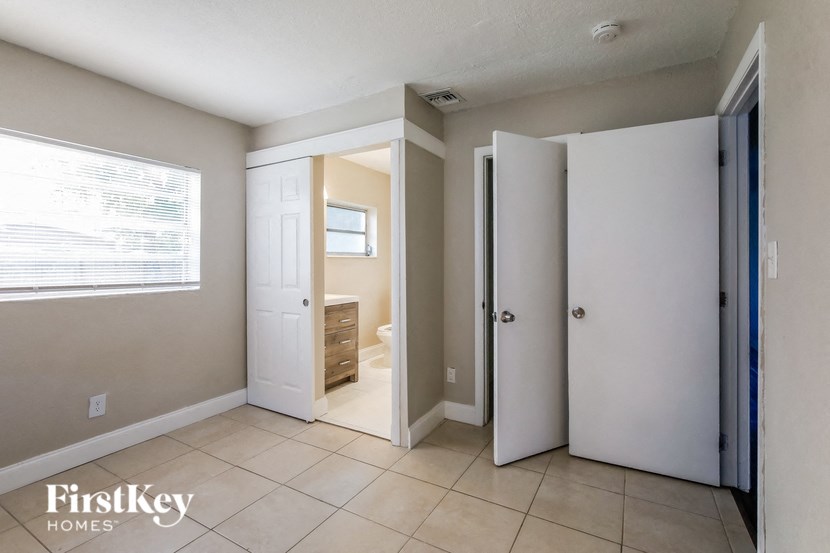 A room with a white door and a window with blinds.
