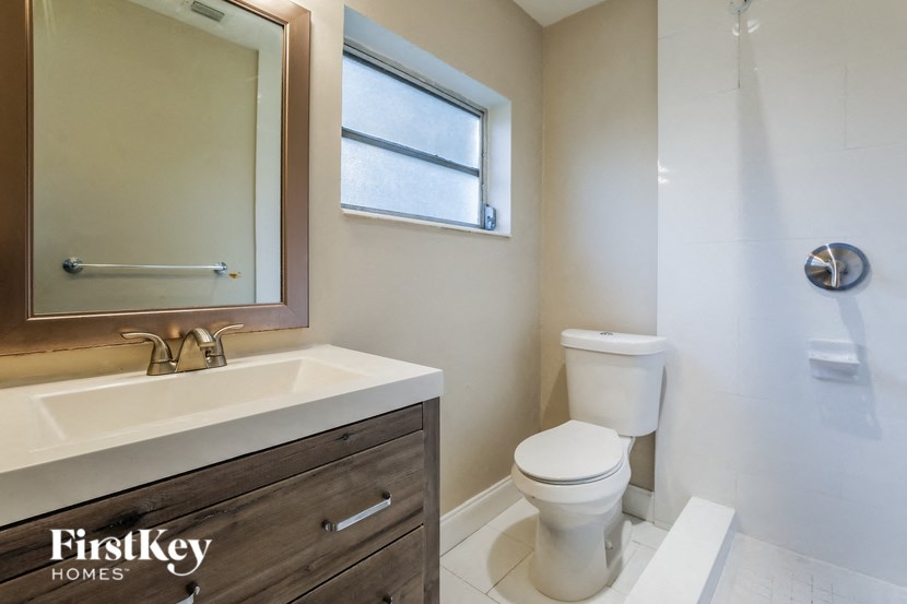 A white toilet sits in a bathroom with a sink and mirror.