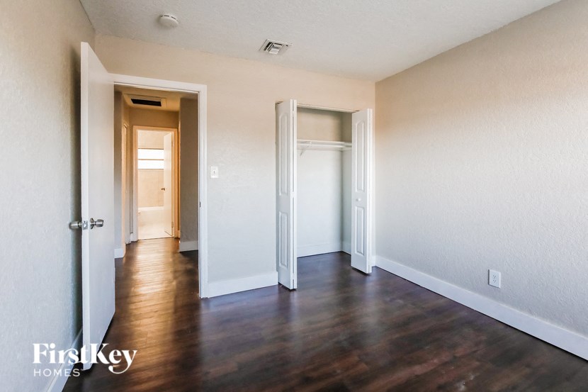 A room with wooden floors and two doors, one of which is open.