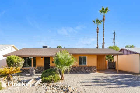 a yellow house with palm trees and a driveway