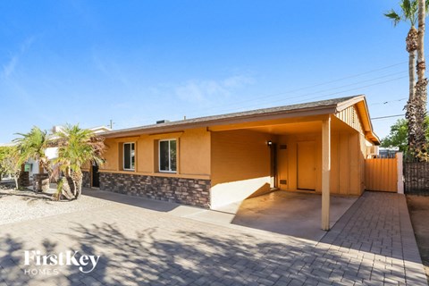 a yellow house with a driveway and a palm tree