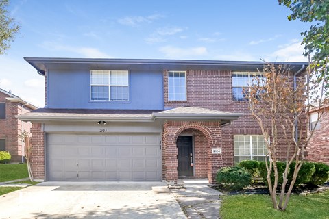 the front of a brick house with a white garage door